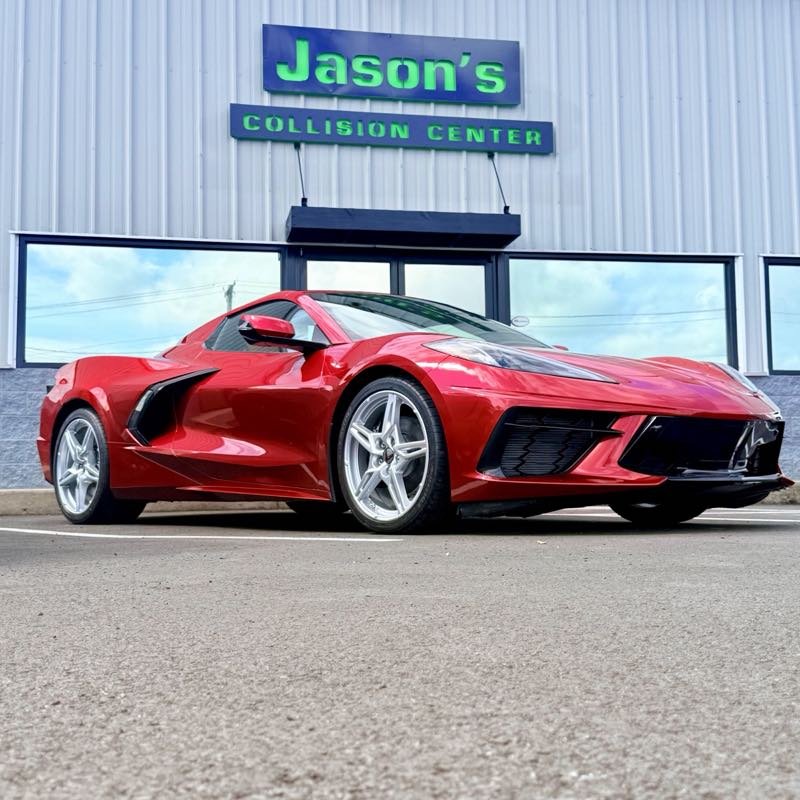 Red Corvette detailed and parked in front of the Jason's Collision Center sign